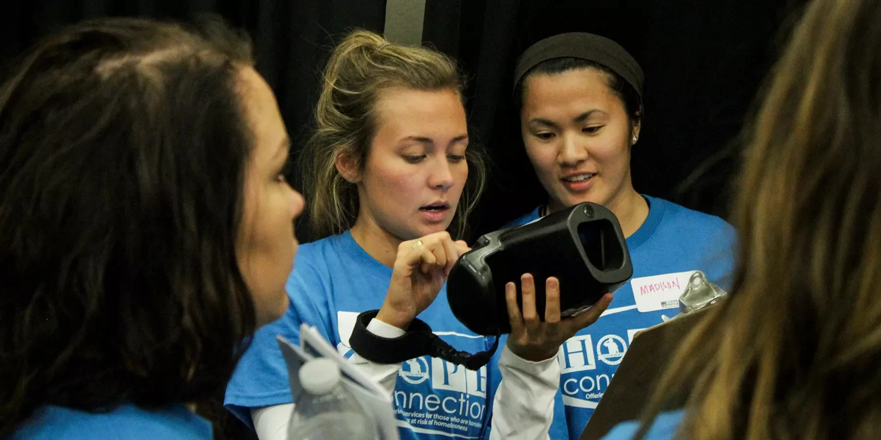 Volunteers in Hope Connection t-shirts examining the screen of a Spot Vision Screener